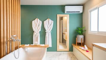 A modern bathroom with a freestanding bathtub, wooden paneling, a mirror, and a potted plant.