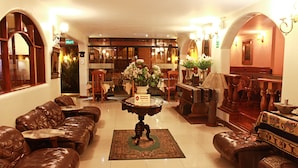A hotel lobby with leather sofas, a central table with a sign, and wooden furniture. - Hotel El Ducado (Lima)