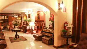 A spacious lobby with leather sofas, a round table with a lamp, and a fire extinguisher on the wall. - Hotel El Ducado (Lima)