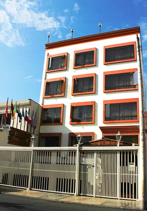 Un immeuble à plusieurs étages, doté d’une façade blanche et de fenêtres à encadrement rouge.