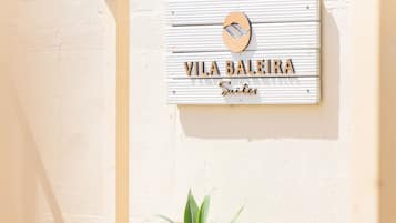 A white outdoor seating area with a sign reading "VILA BALEIRA Suites".