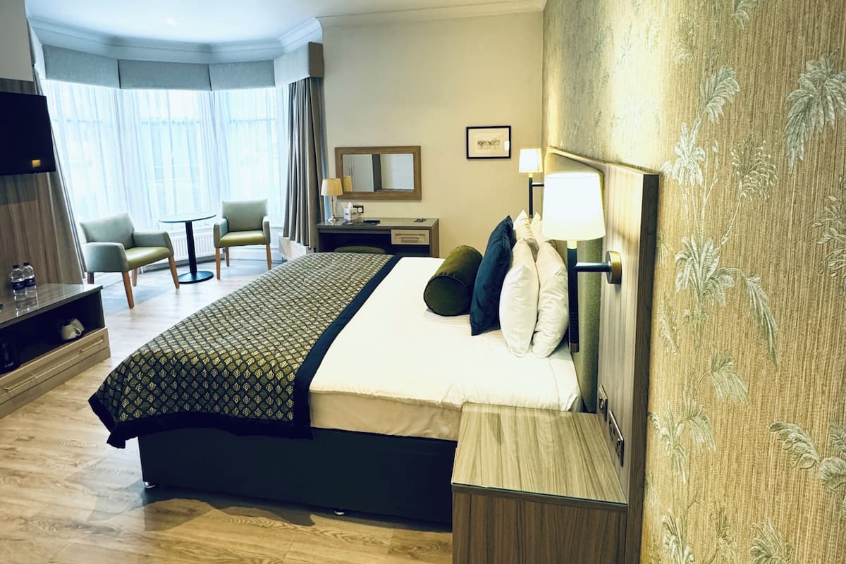 Een hotelkamer met een groot bed, nachtkastjes, een bureau, een stoel en een televisie.