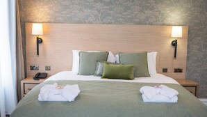 Une chambre d’hôtel avec un lit, deux lampes de chevet, un téléphone et un lit bien fait, agrémenté de serviettes.