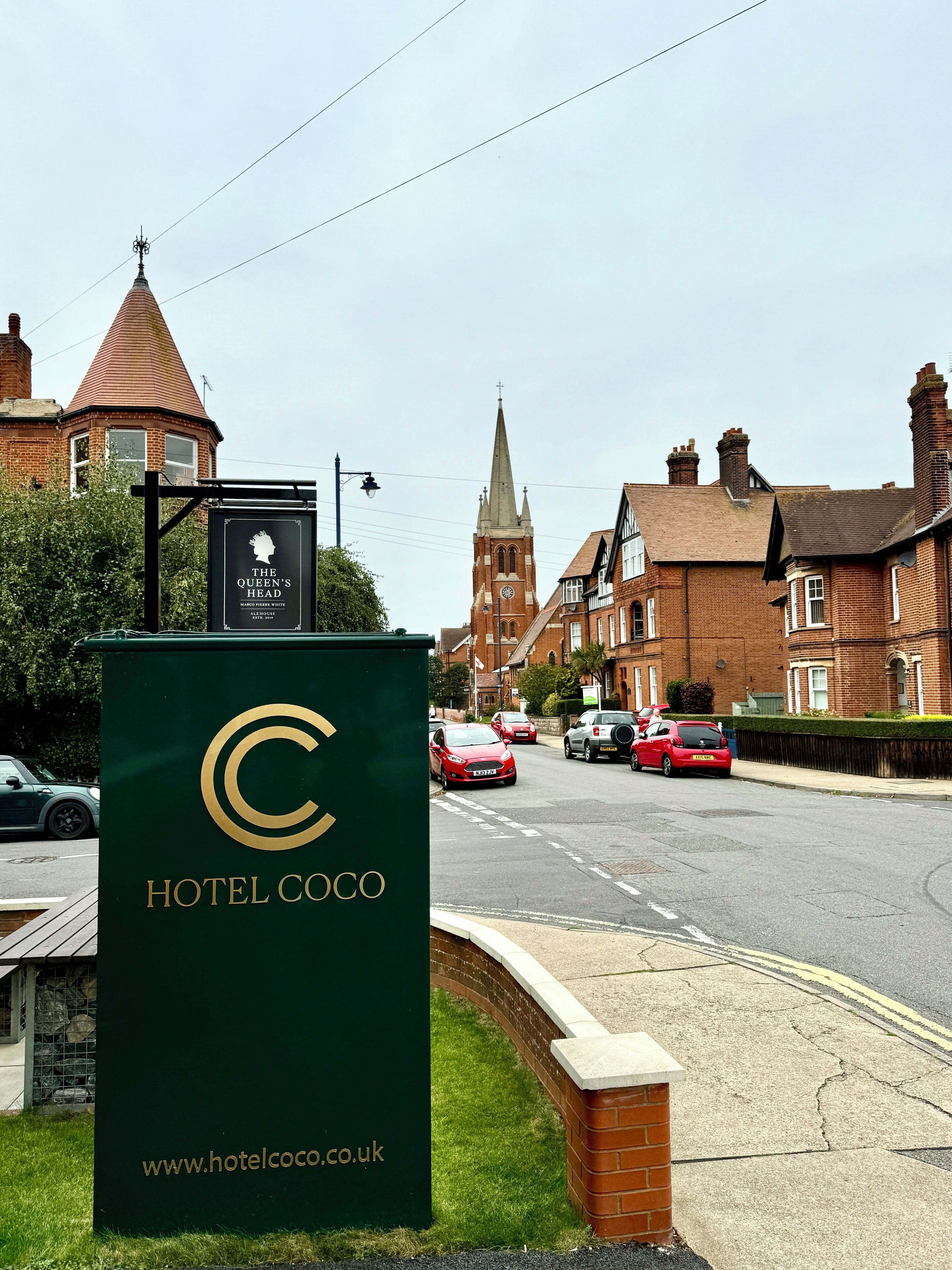 A street view with a Hotel Coco sign, a church, and residential buildings.