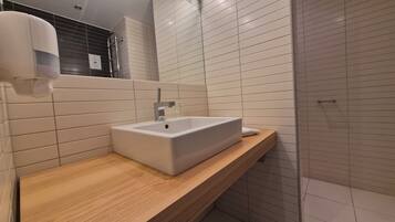 A modern bathroom with a rectangular sink, wooden countertop, and tiled walls.