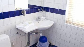 Ett badrum med ett vitt handfat, en spegel, en toalett och blå kakelplattor på golvet.
