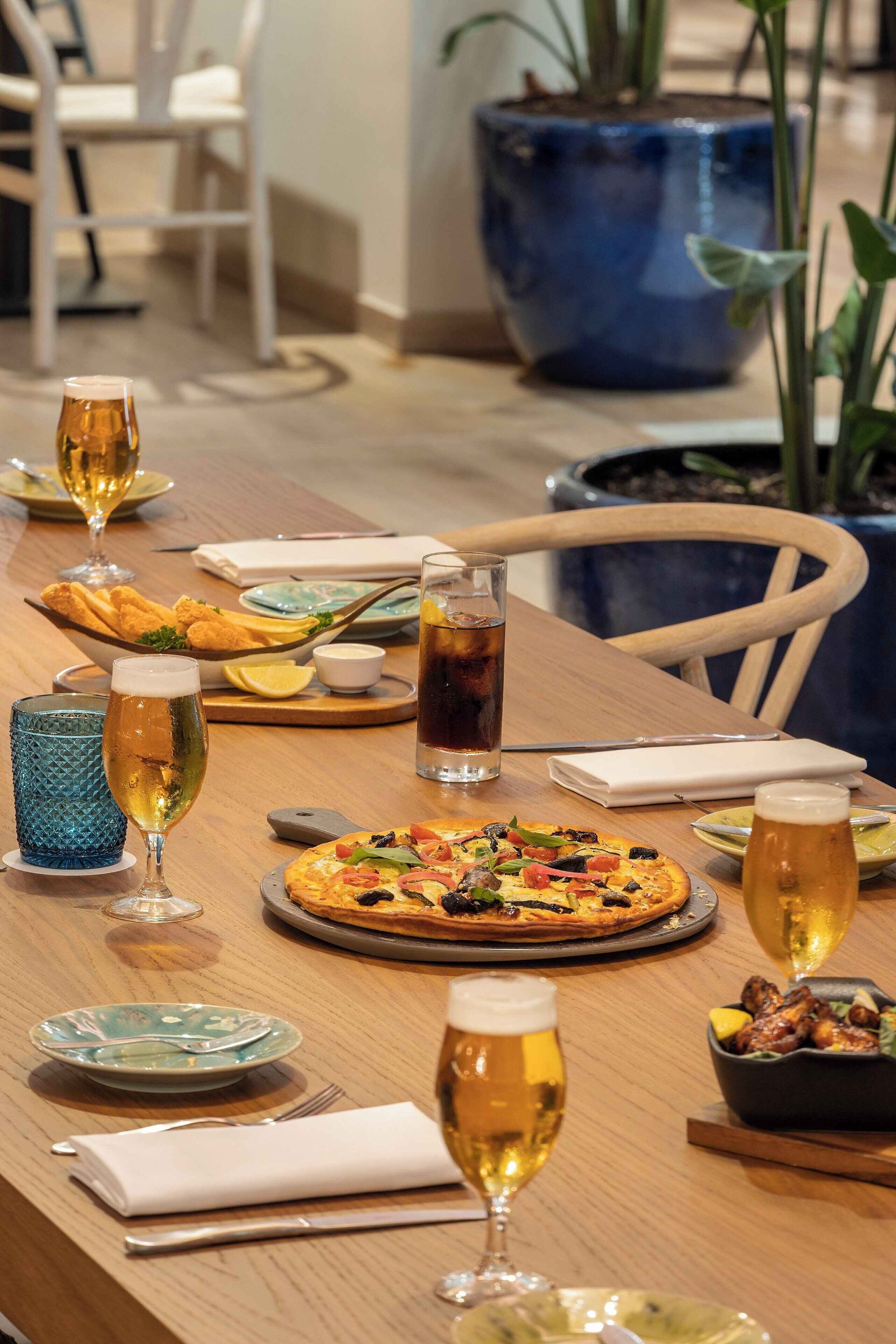 A dining table set with various dishes, drinks, and a pizza.