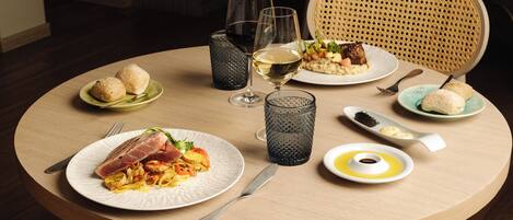 A round dining table with plates of food, glasses, and cutlery.