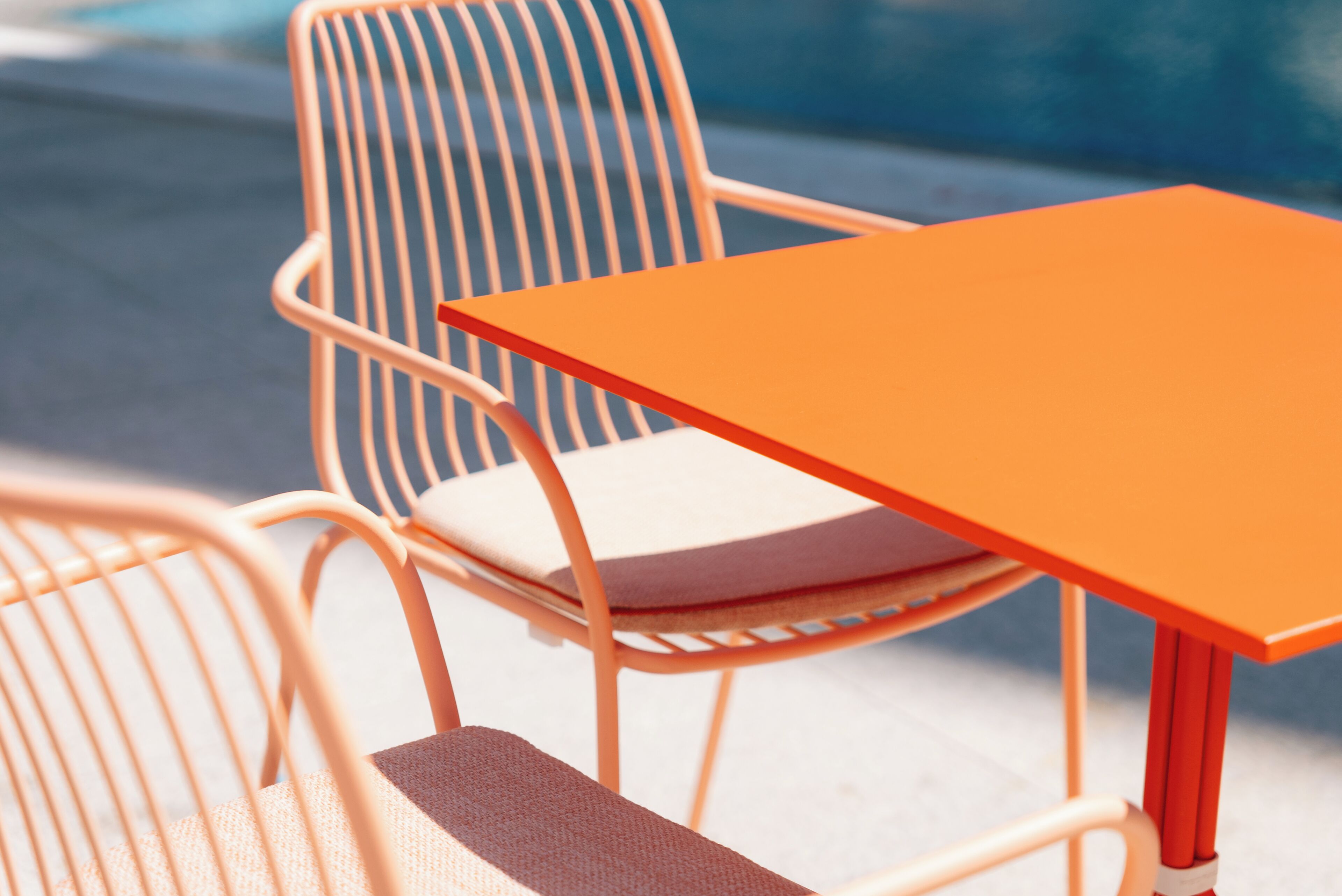 Un gros plan d’une chaise en métal avec un coussin et une table orange.