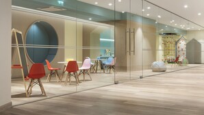 A modern interior with glass walls, wooden flooring, and colorful chairs. - Crowne Plaza Caparica Lisbon by IHG (Almada)
