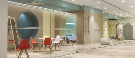 A modern interior with glass walls, wooden flooring, and colorful chairs.