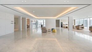 A spacious lobby with a high ceiling, a central seating area, and a view of the adjacent kitchen area. - Crowne Plaza Caparica Lisbon by IHG (Almada)