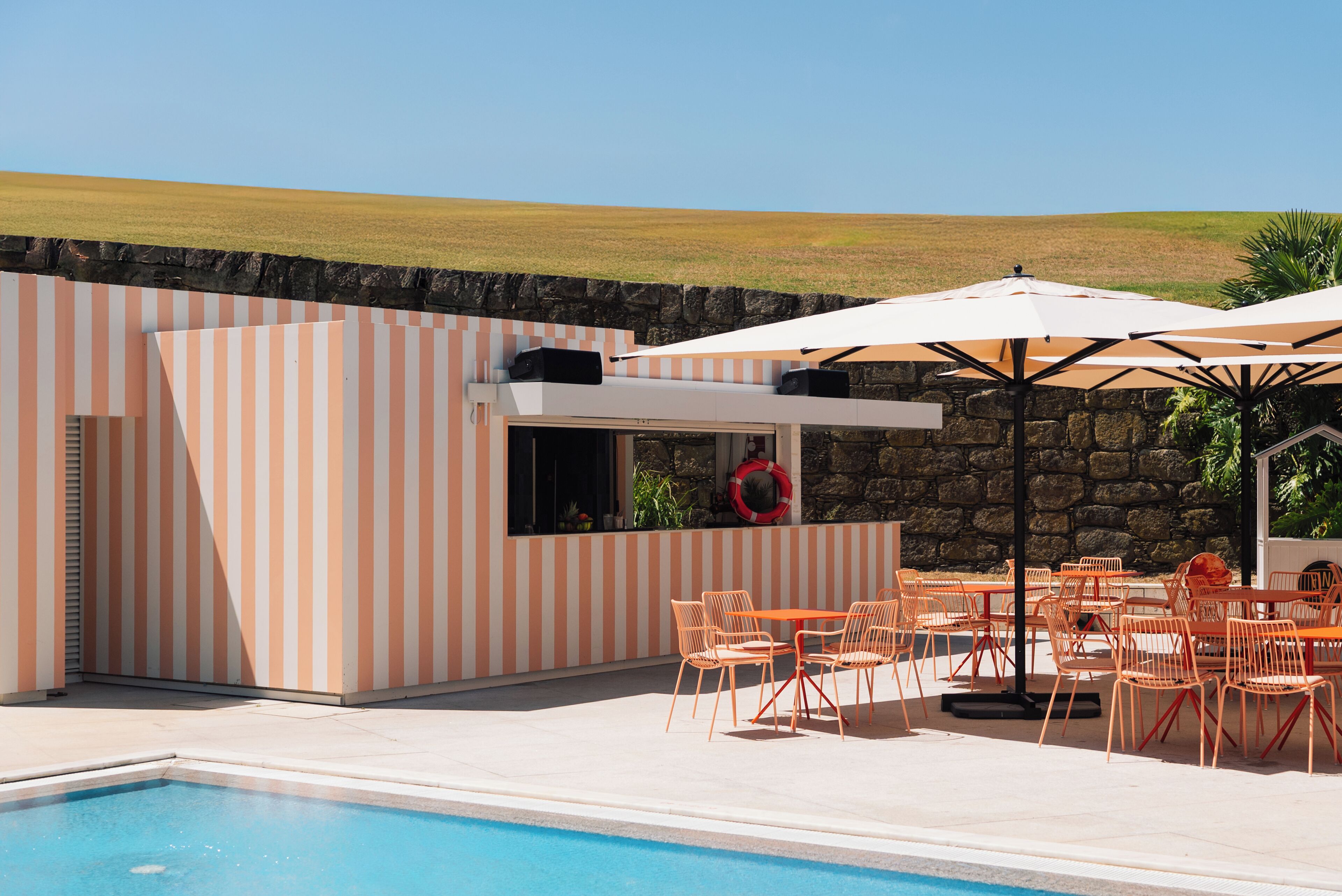 A poolside area with striped walls, outdoor seating, and a lifebuoy.