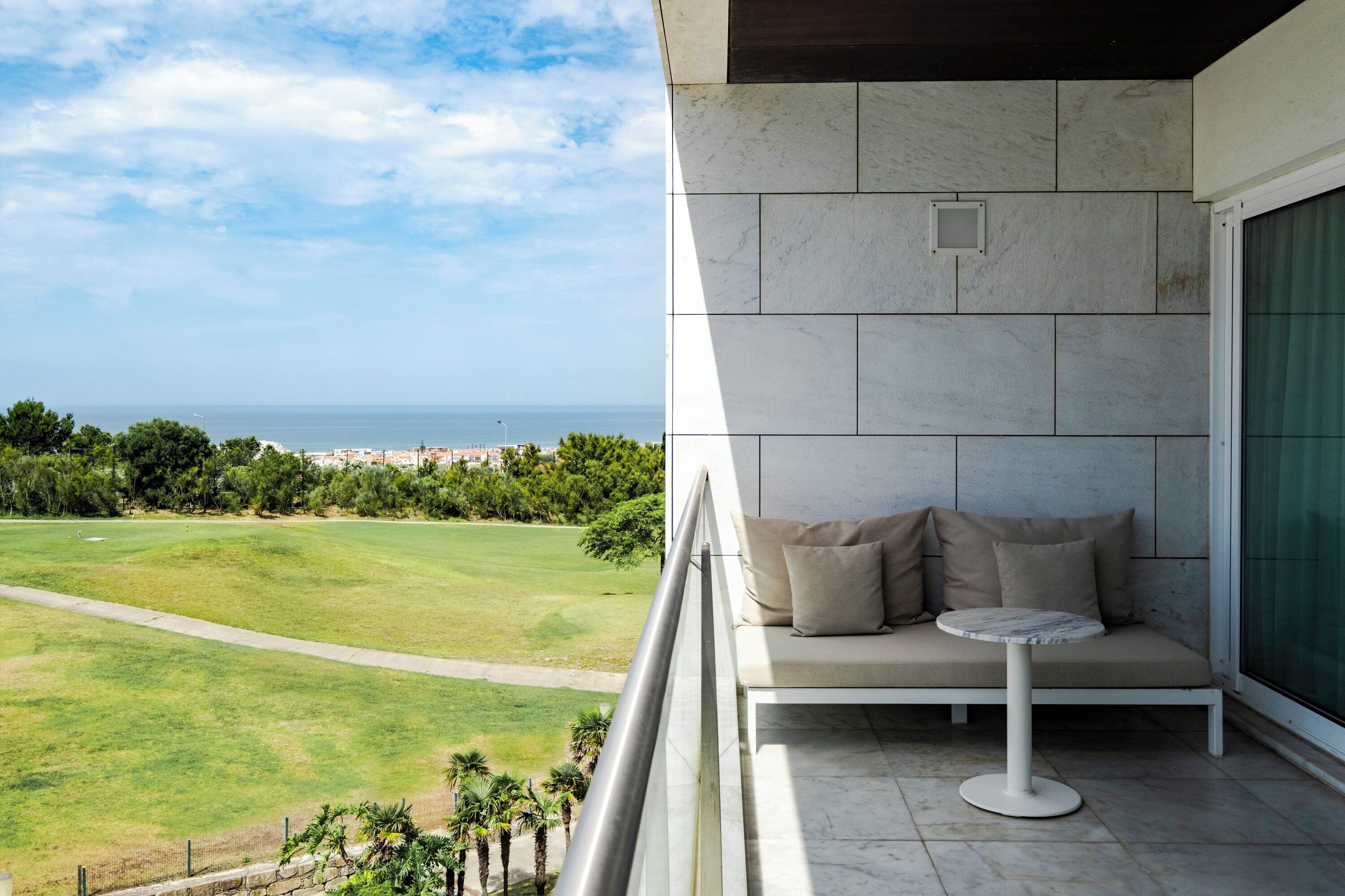 A balcony with a view of a green landscape and the sea.