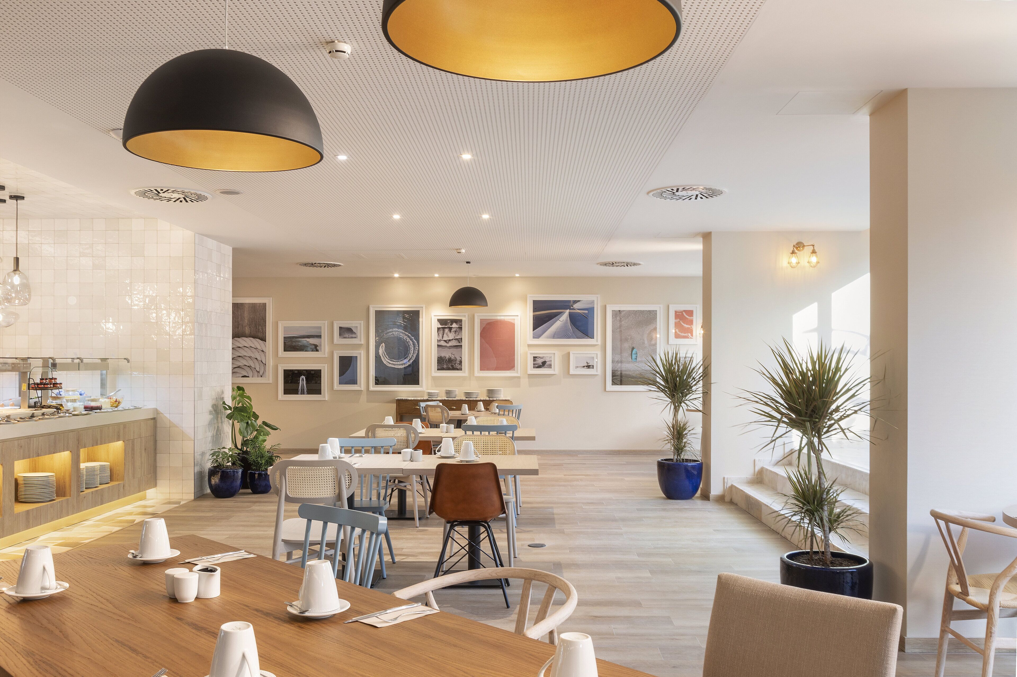 Un espace repas moderne avec une longue table en bois, des chaises et un comptoir où est affiché le menu.