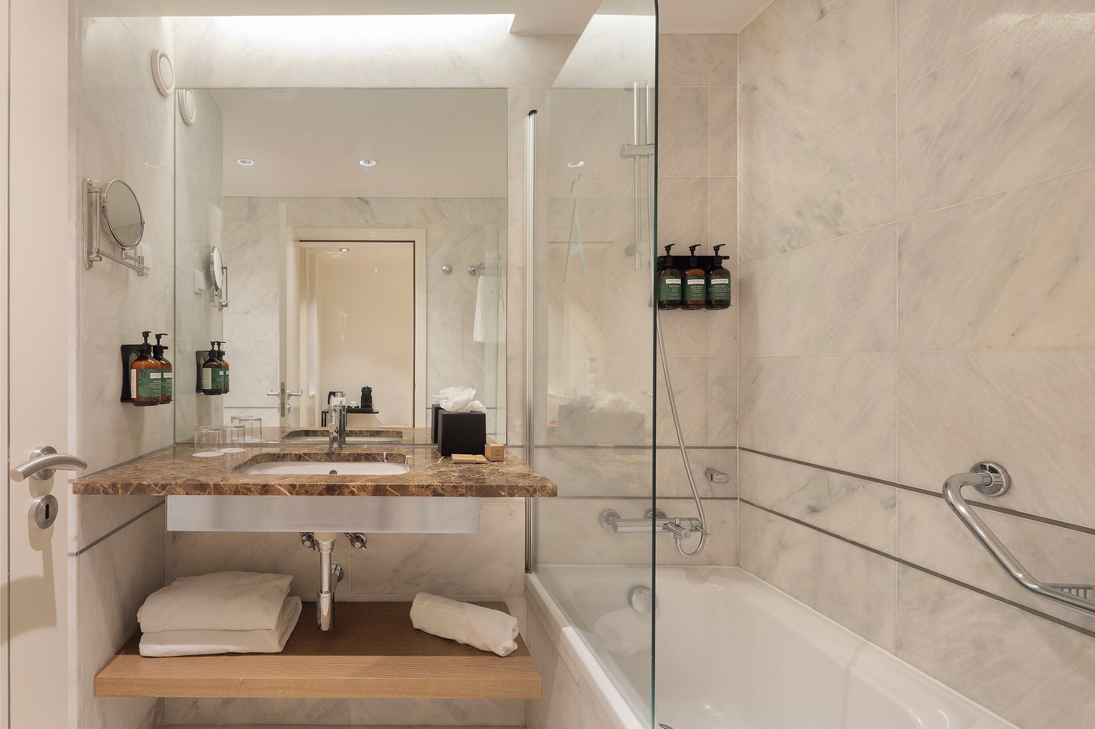 Un baño moderno con lavamanos de mármol, cabina de ducha de vidrio y bañera.