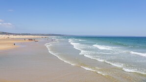 A beach with clear skies, gentle waves, and a sandy shore. - Crowne Plaza Caparica Lisbon by IHG (Almada)