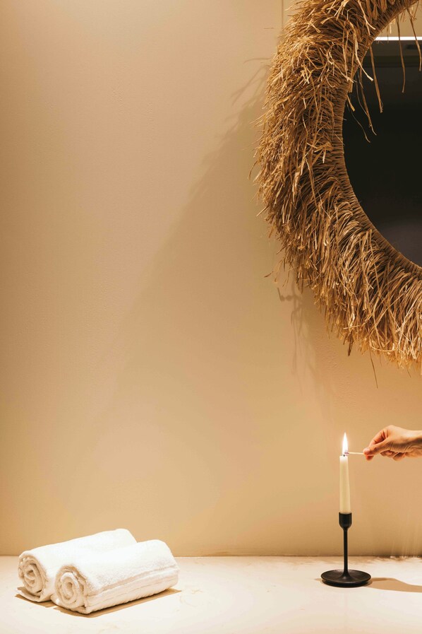 A candle on a black holder, a rolled white towel, and a straw wreath on a wall. - Crowne Plaza Caparica Lisbon by IHG (Almada)