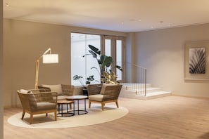 A modern living room with wicker furniture, a round coffee table, and a large potted plant.