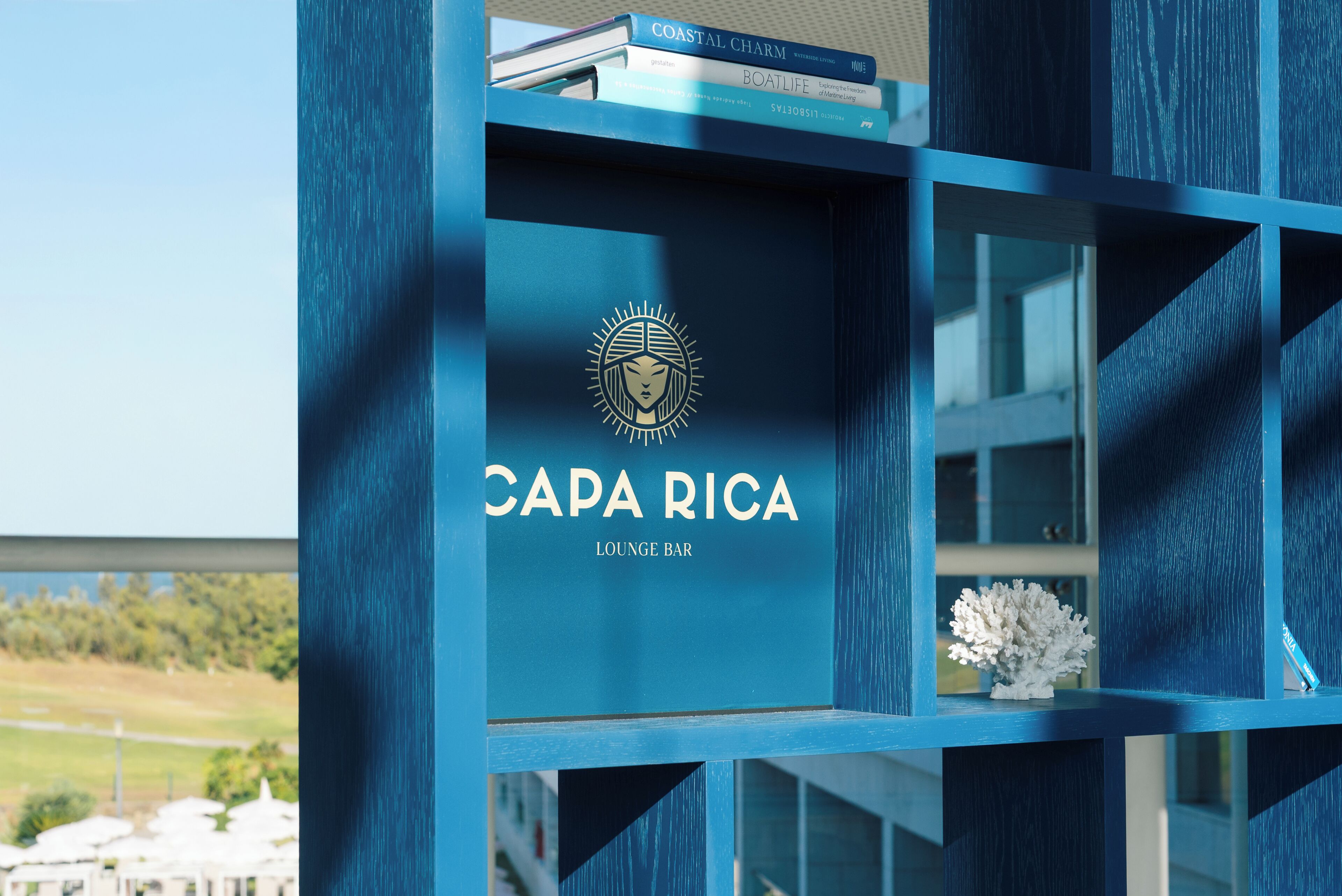 Ein blaues Bücherregal mit dem Schriftzug "CAPA RICA LOUNGE BAR" und einem Logo.