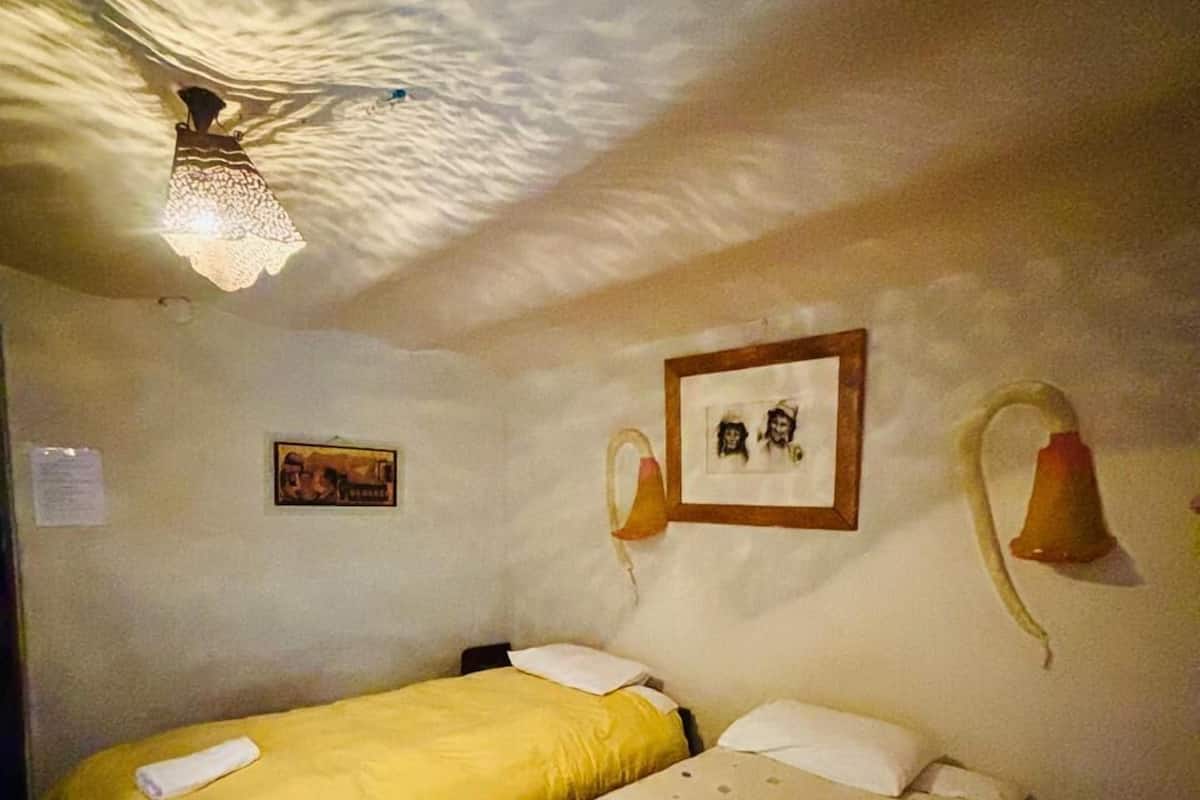Ein Zimmer mit zwei Betten, einem Deckenventilator und Wandleuchten.