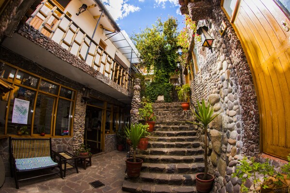 A stone staircase leading to a wooden door, surrounded by potted plants and a bench. - Casa de Campo Cusco (Cusco)