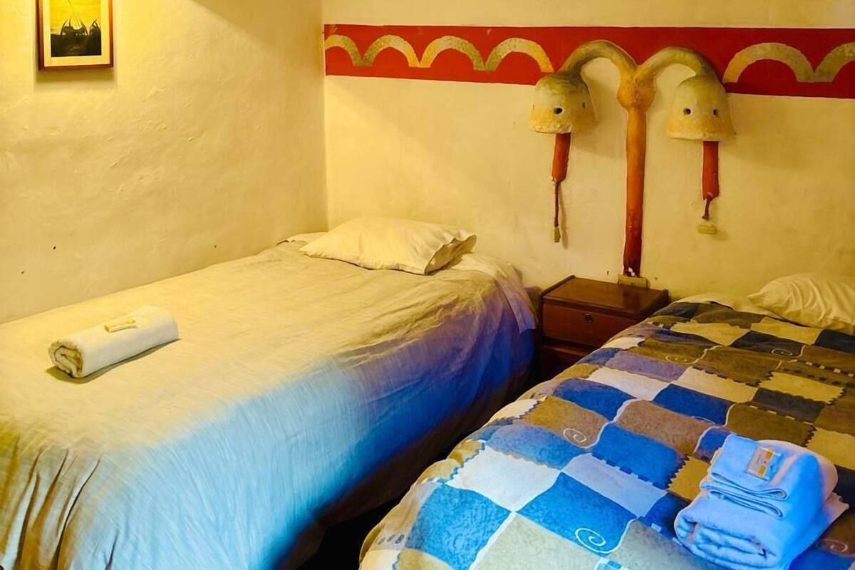 Ein Zimmer mit zwei Betten, einer Wandlampe und einem gerahmten Bild.