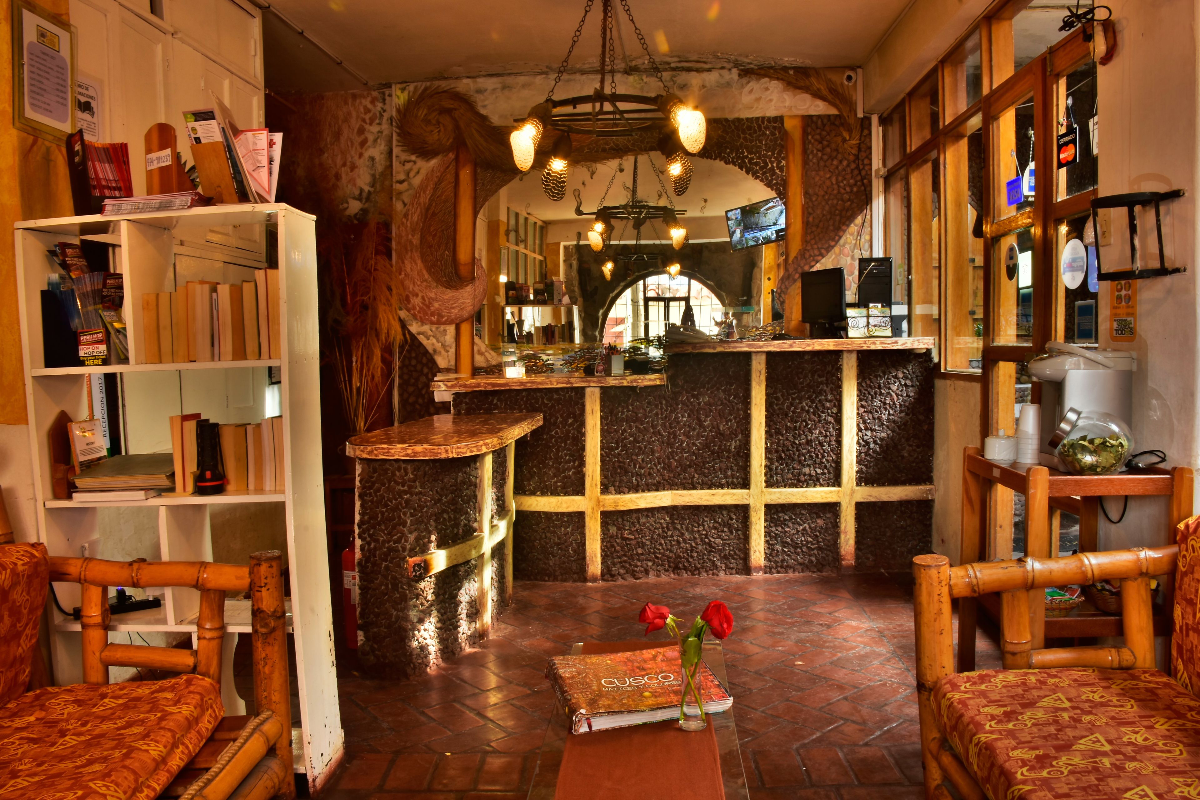 A cozy interior with a reception desk, wooden furniture, and a book titled 'Cusco'.