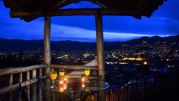 A table with drinks and candles, overlooking a cityscape at night. - Casa de Campo Cusco (Cusco)
