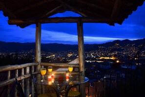 A table with drinks and candles, overlooking a cityscape at night. - Casa de Campo Cusco (Cusco)