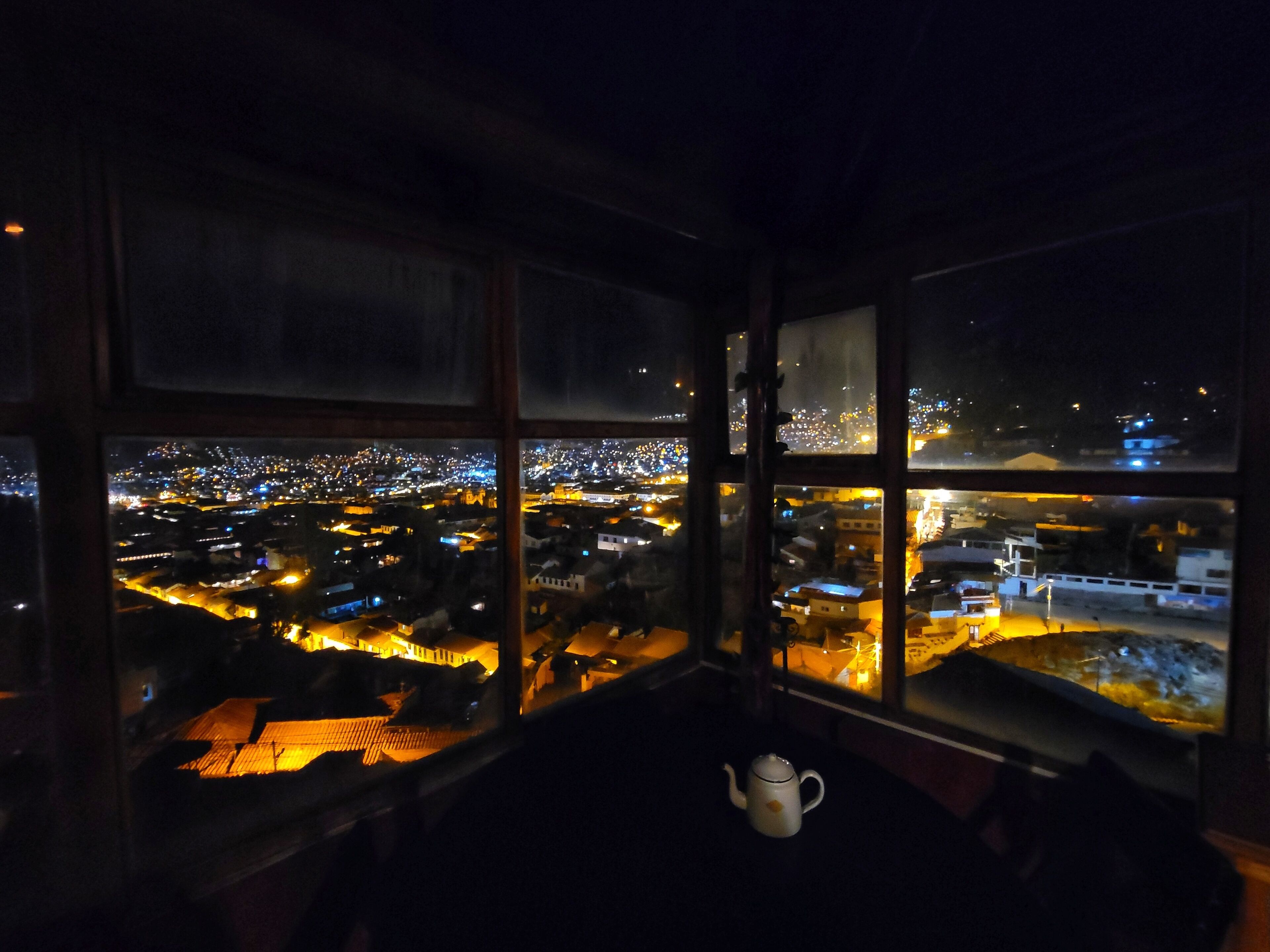 A room with a view of a city at night through large windows.