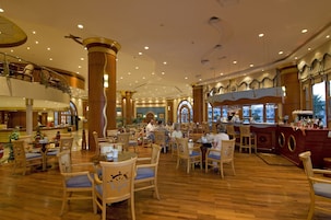 A spacious hotel lobby with wooden flooring, multiple dining areas, and a bar with a nautical theme.