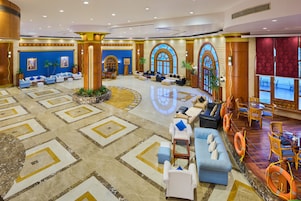 A spacious lobby with a central seating area, large windows, and a decorative floor pattern.