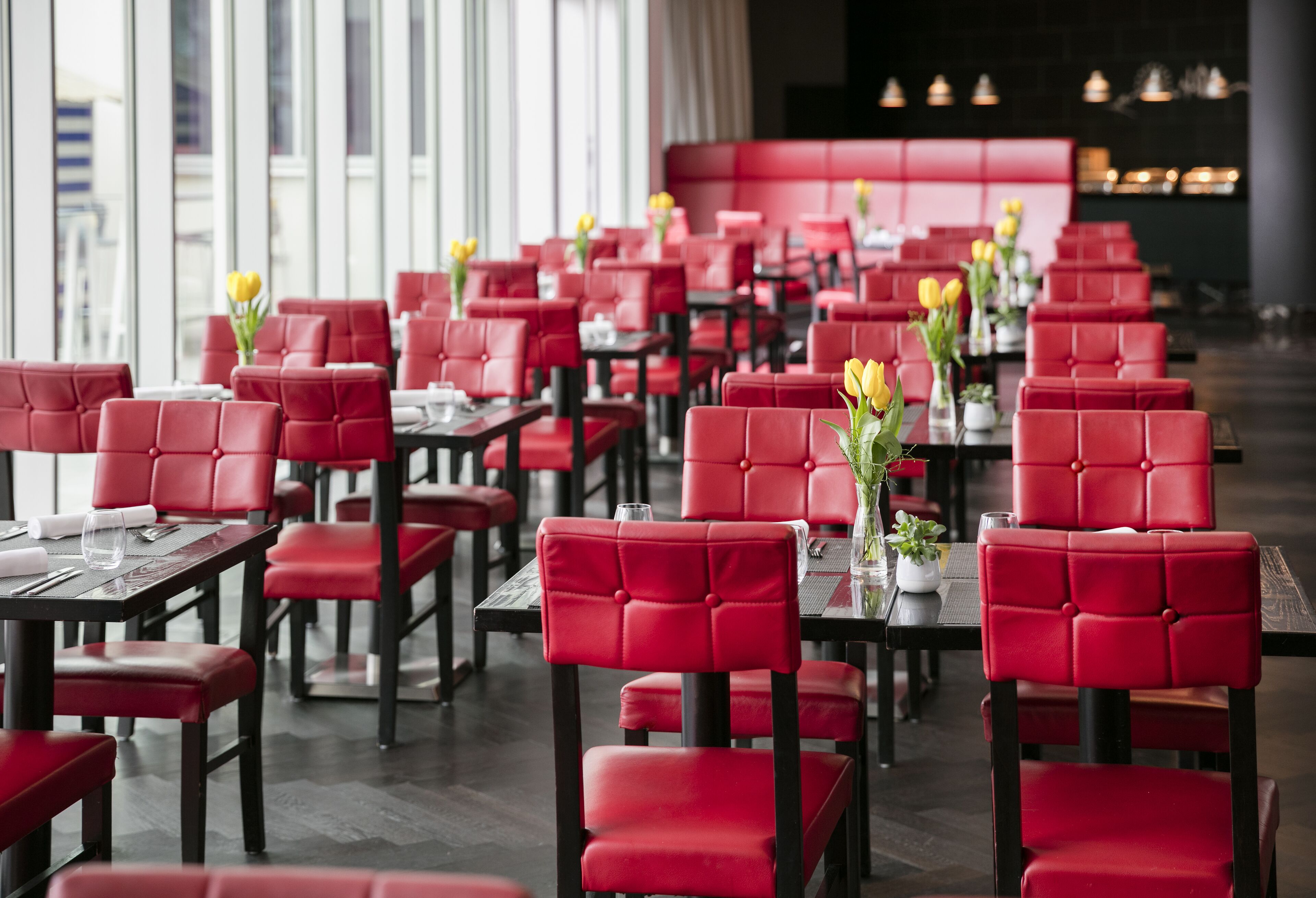 Een restaurant met rode bekleden stoelen en tafels, in rijen gerangschikt.