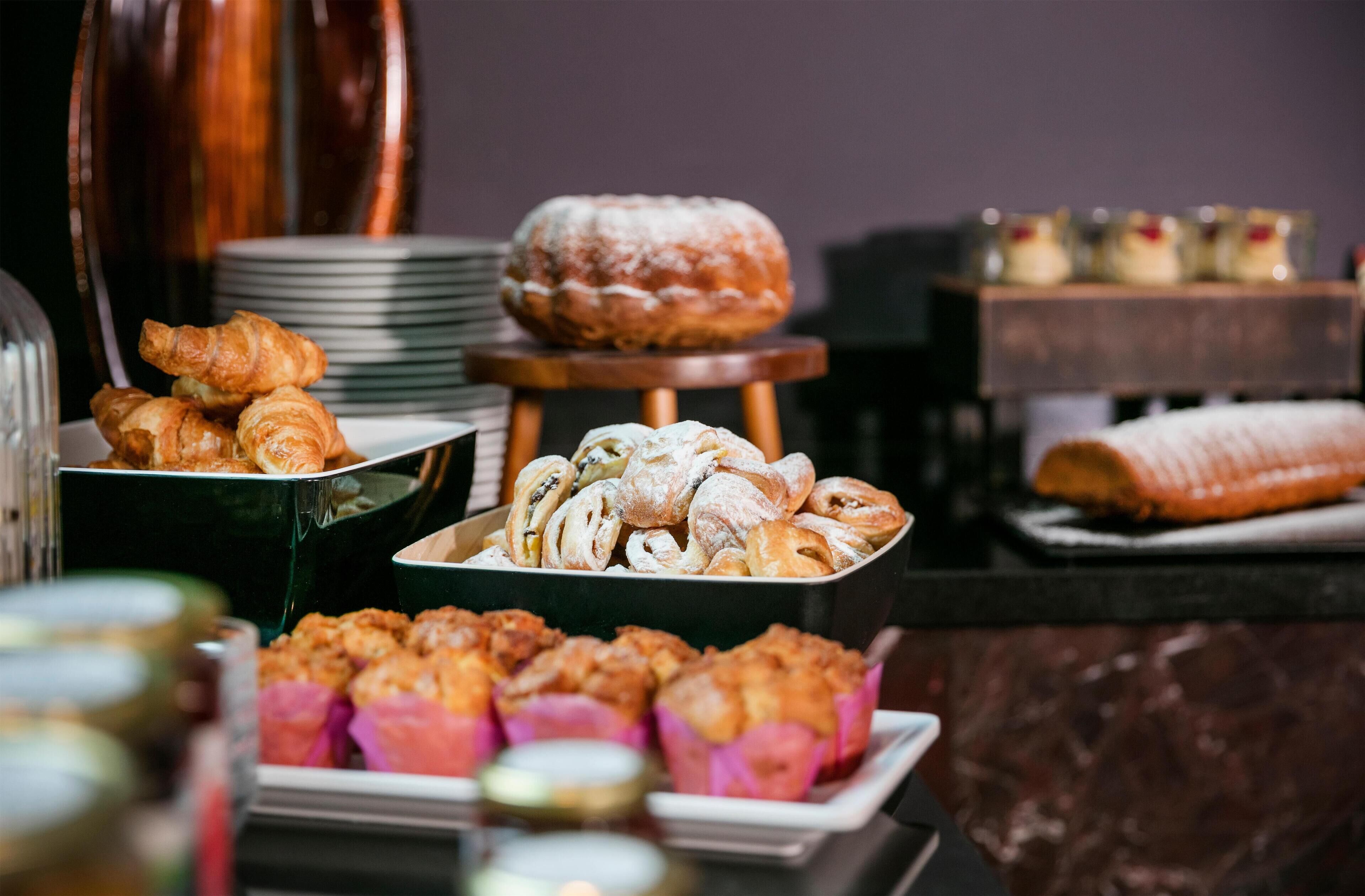 Un bufé con diversas opciones de pastelería y postres, incluyendo cruasanes y un pastel ring.