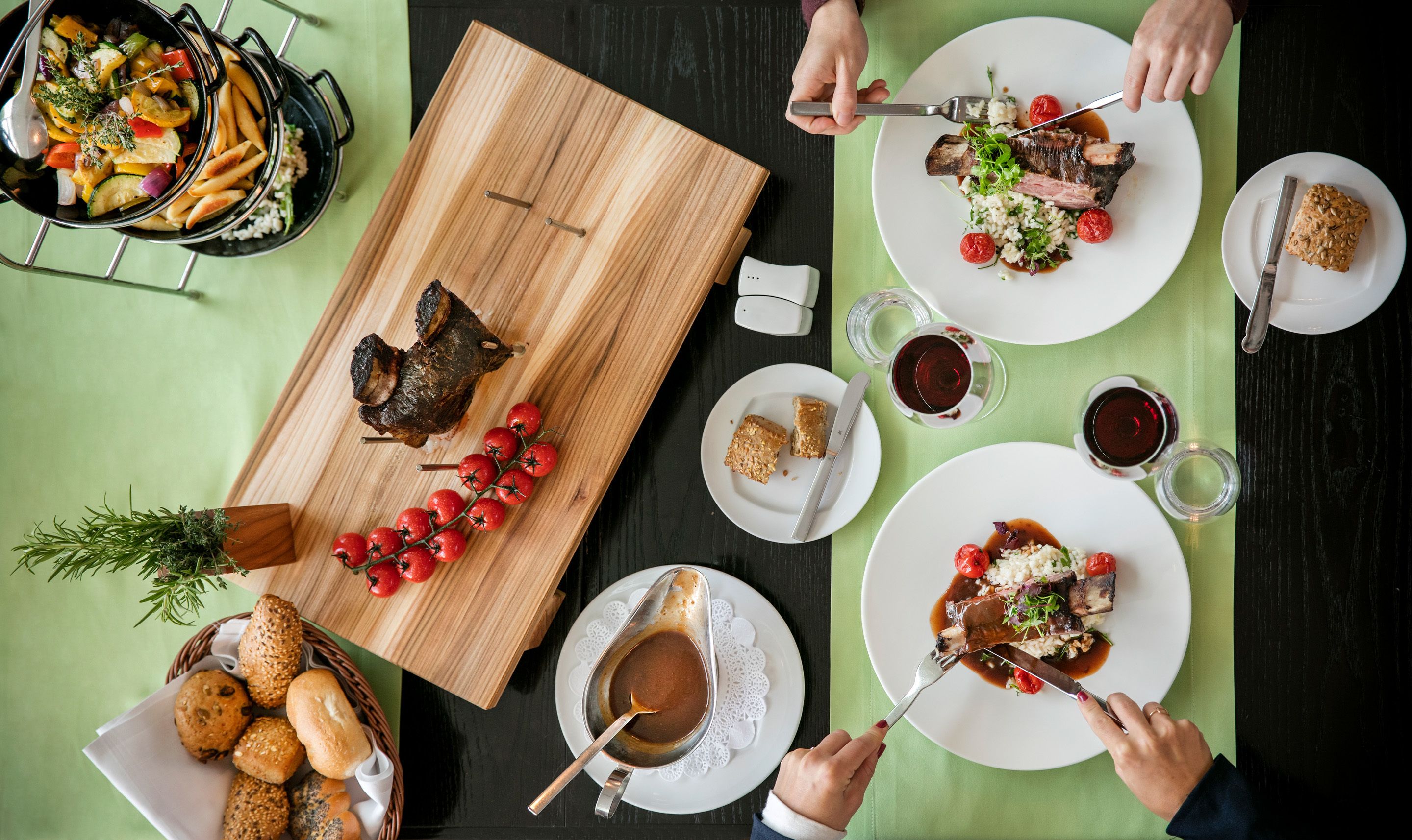 A dining table with various dishes, including a roasted duck, vegetables, and bread.