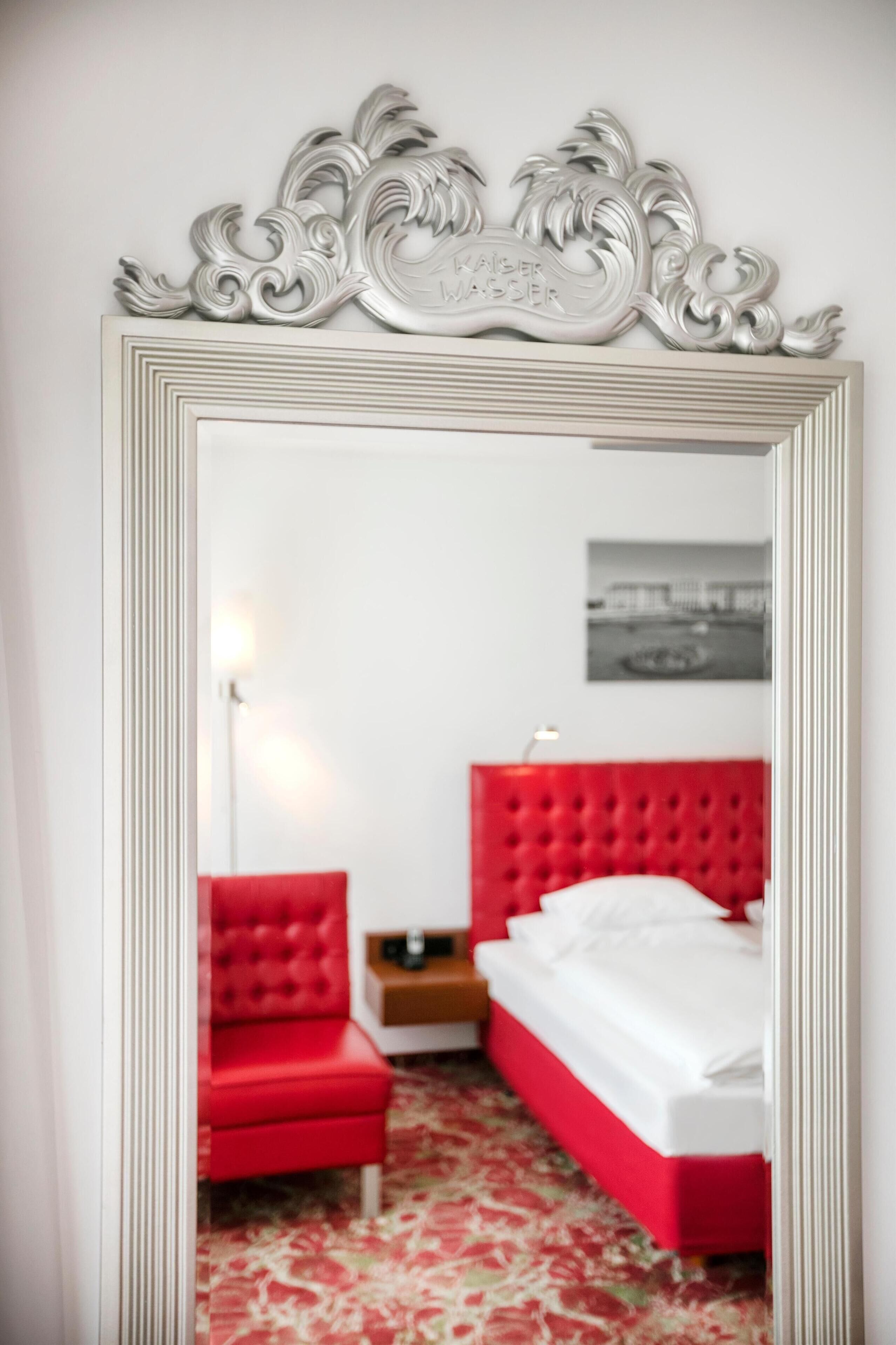 Une chambre à coucher avec un fauteuil rouge rembourré, une tête de lit rouge et un lit blanc.