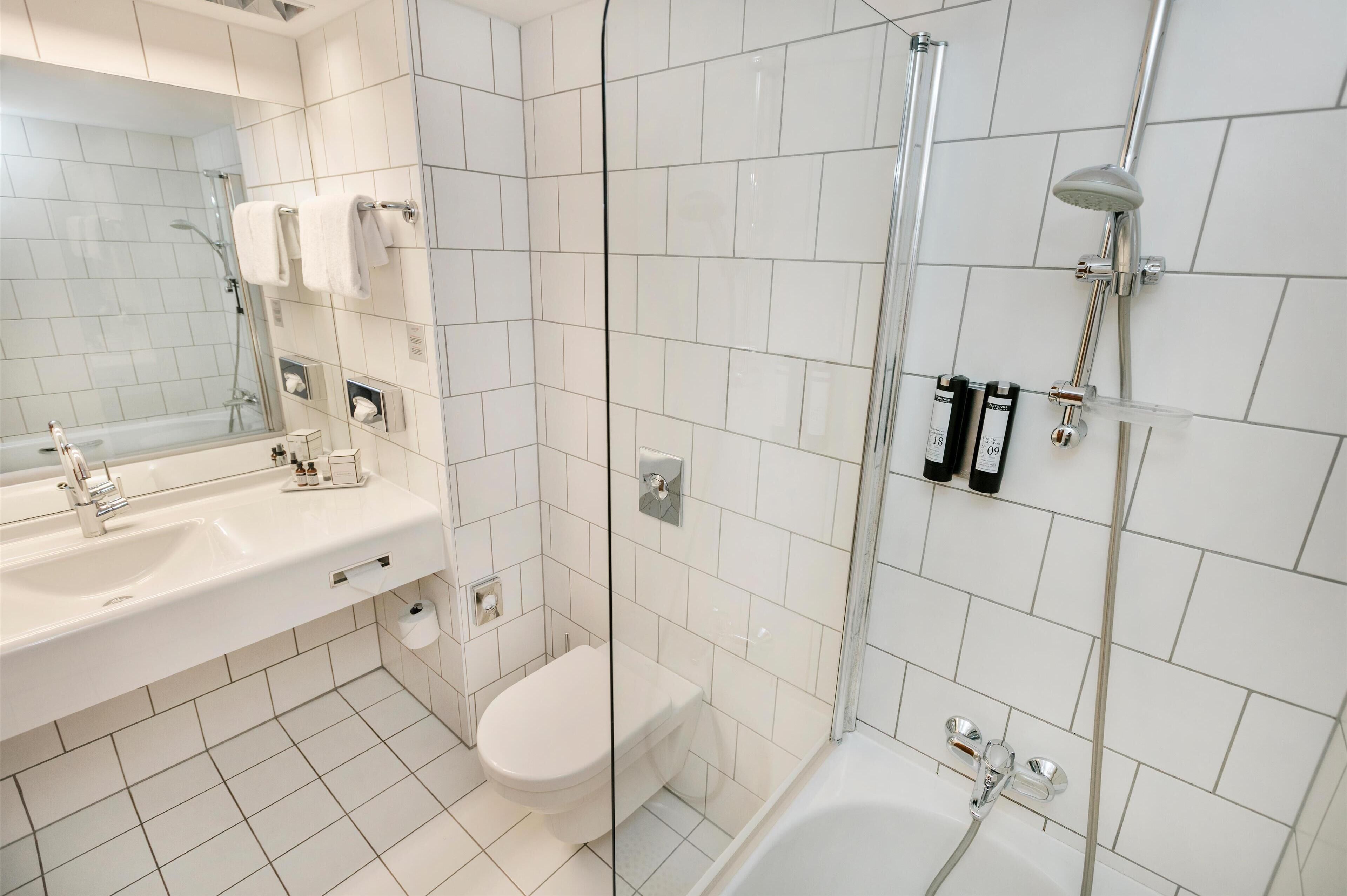 Une salle de bain moderne avec une douche à parois de verre, un lavabo blanc et des toilettes.