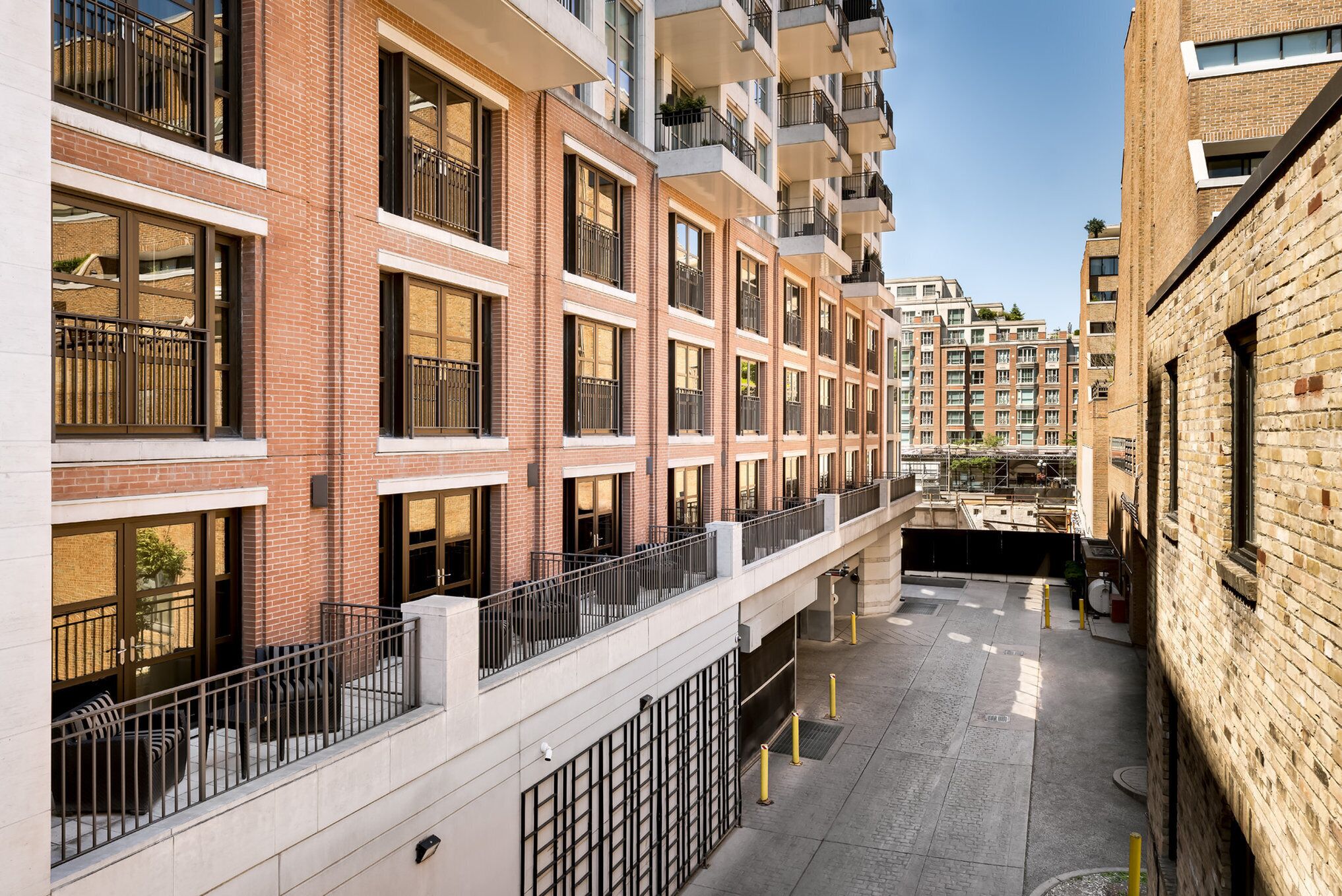 A multi-story residential building with balconies, large windows, and a brick facade.