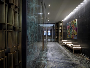 A modern elevator interior with a marble floor, a decorative ceiling light, and a potted plant on the left. at The Hazelton Hotel Toronto