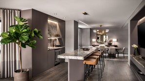 Una cocina moderna con encimera de mármol, taburetes de bar y una planta en maceta grande.