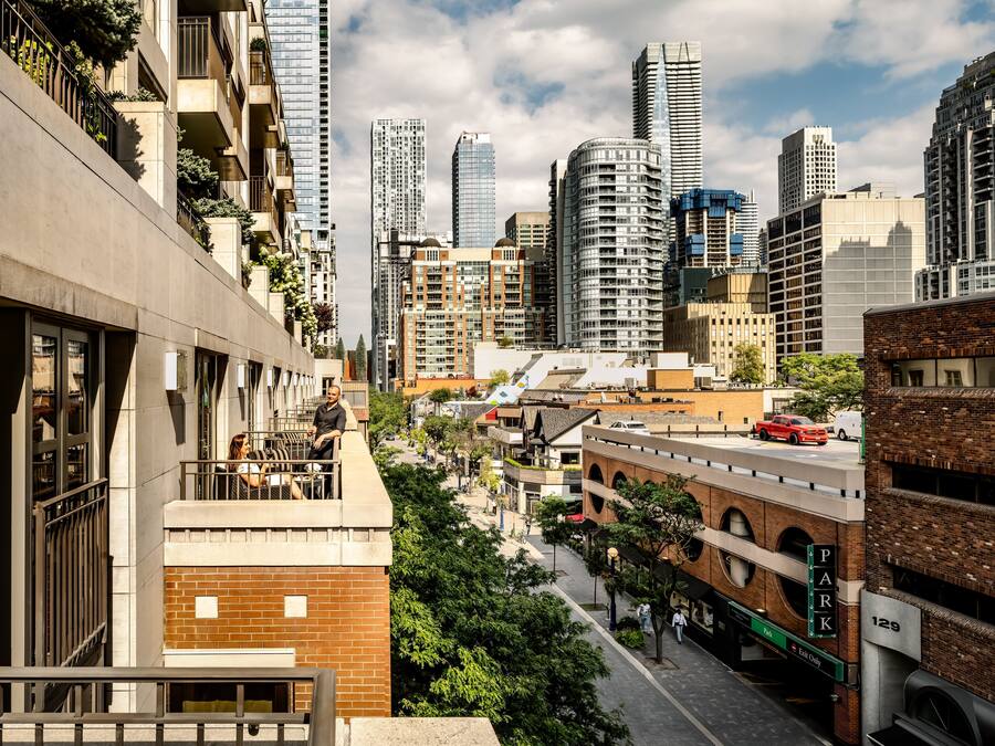 A high-rise building with multiple floors, a parking garage, and a street with vehicles.