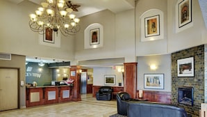 A spacious lobby with a reception desk, leather seating, a chandelier, and a fireplace.