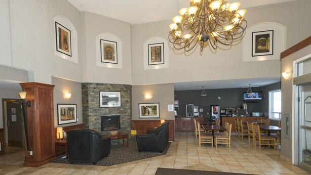 A spacious living area with a fireplace, comfortable seating, a dining area, and a kitchen in the background.