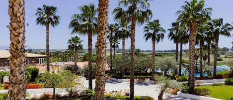 A resort with palm trees, a pool, and a well-maintained lawn.