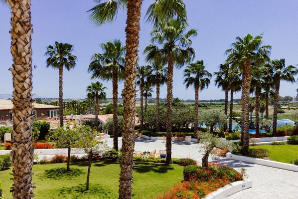 Un resort con palme, piscina e un prato curato.