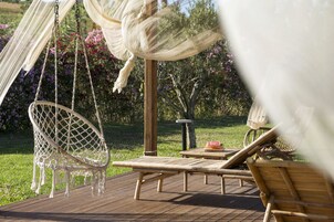 Eine Holzterrasse mit einer Hängematte, einer Liege und einem Tisch mit einem Buch.