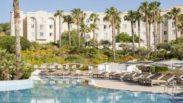 A resort with a pool, lounge chairs, and palm trees.