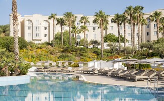 Un resort con piscina, sillas de descanso y palmeras.