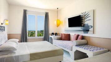 Una habitación de hotel con cama, sofá, televisor y ventana con cortinas.